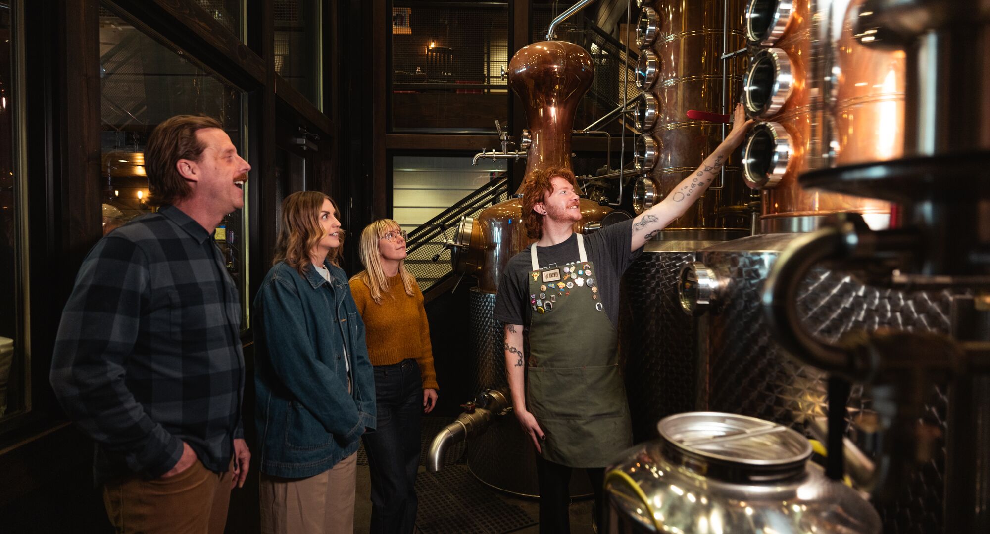 Three people take part in the PARK Distillery on-site tour with a guide in Banff National Park.